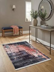Tapis rectangulaire aux motifs abstraits gris foncé, corail et bleu clair, avec franges, dans un couloir lumineux au parquet clair