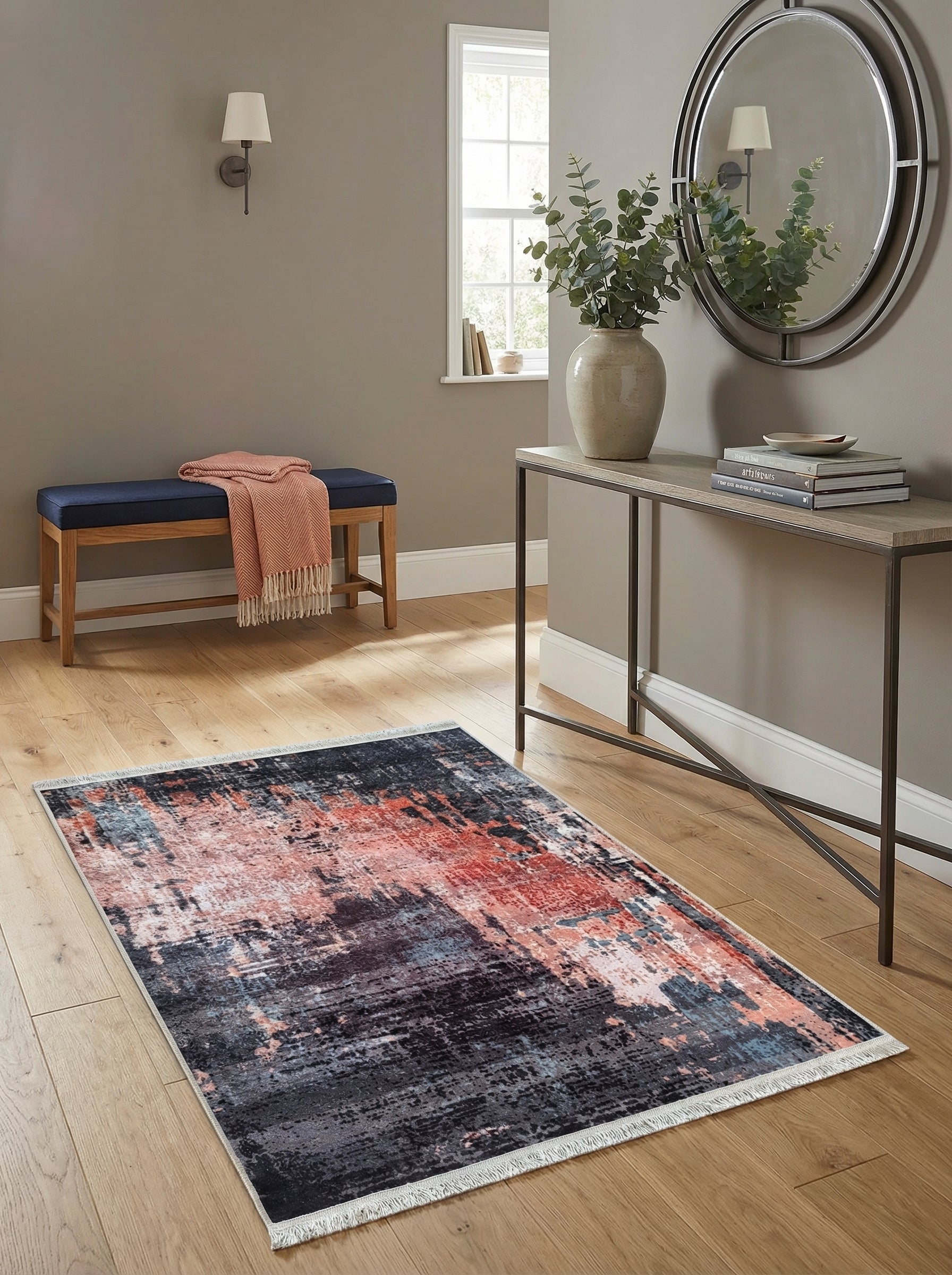 Tapis rectangulaire aux motifs abstraits gris foncé, corail et bleu clair, avec franges, dans un couloir lumineux au parquet clair