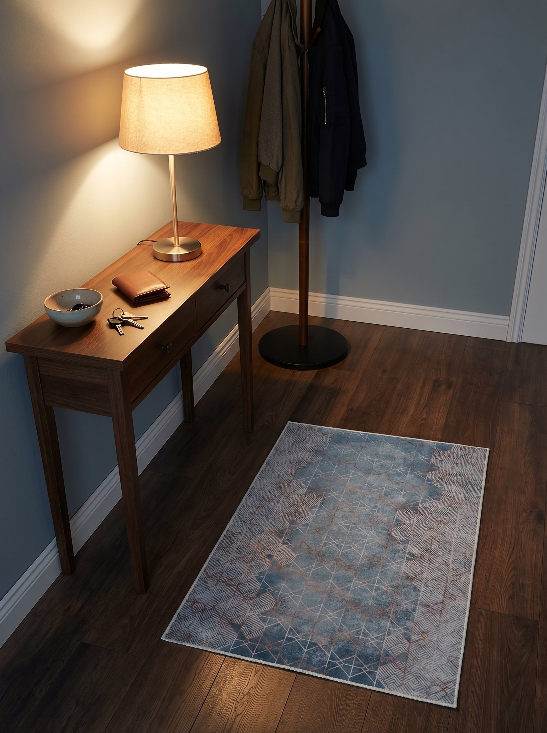 Tapis rectangulaire bleu dégradé à motifs géométriques cuivrés et zones à chevrons gris clair, dans une entrée