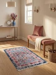Tapis rectangulaire vintage bleu marine, turquoise et rose aux motifs floraux, avec franges, sur un parquet clair dans une entrée