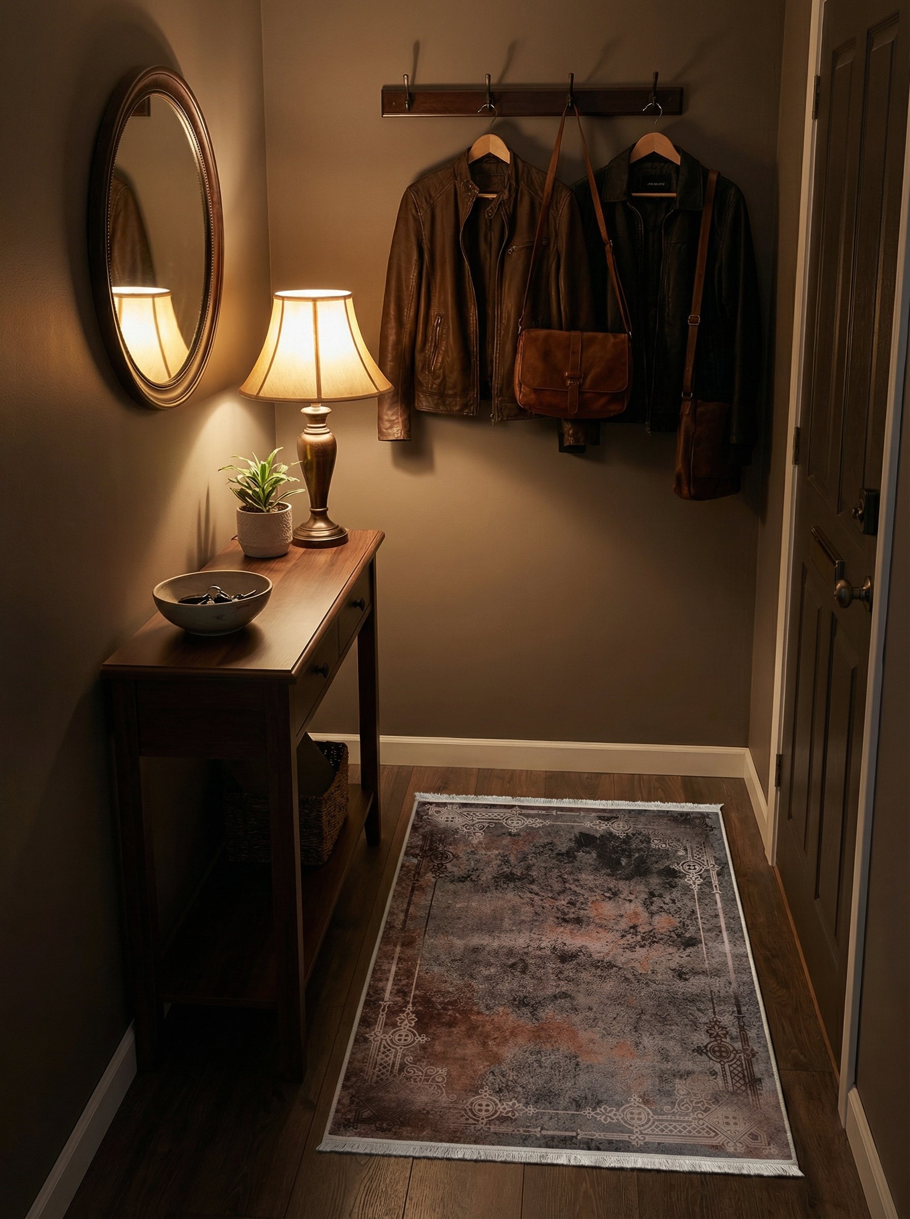Tapis rectangulaire à motifs abstraits gris foncé et rouille avec une bordure ornementale beige clair, posé dans une entrée