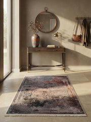 Tapis rectangulaire aux motifs abstraits nuancés de gris foncé, terre cuite et beige, avec des bordures ornementales claires, dans une entrée
