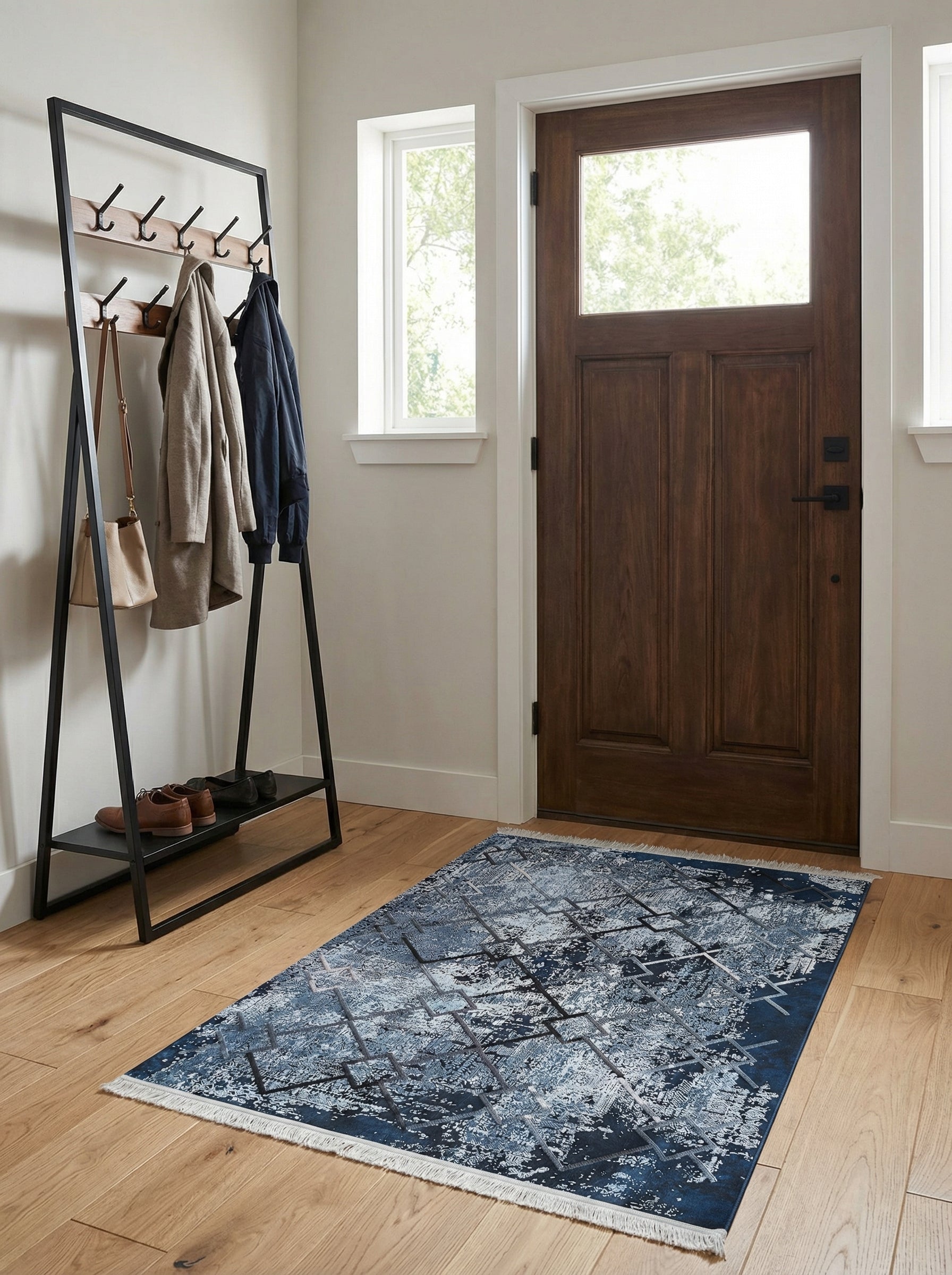 Tapis rectangulaire bleu foncé et clair, motifs abstraits et géométriques gris, avec des franges blanches dans une entrée