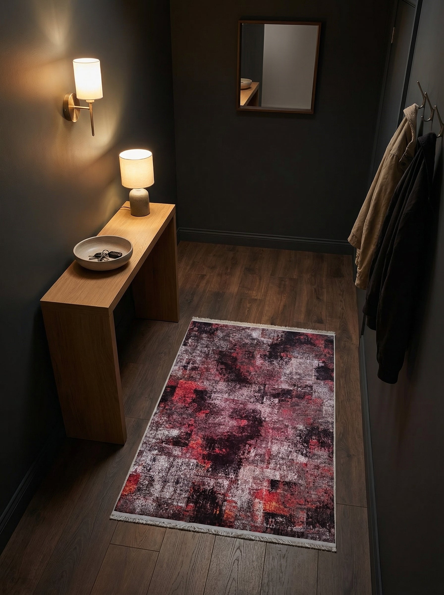 Tapis rectangulaire abstrait aux teintes délavées de bordeaux, noir et blanc, sur parquet sombre d'une entrée