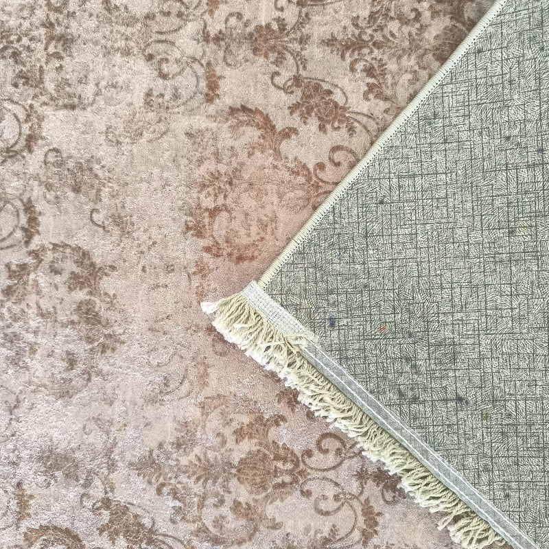 Tapis à motifs floraux baroques beige et marron, une partie est relevée pour montrer son envers quadrillé vert-gris et ses franges