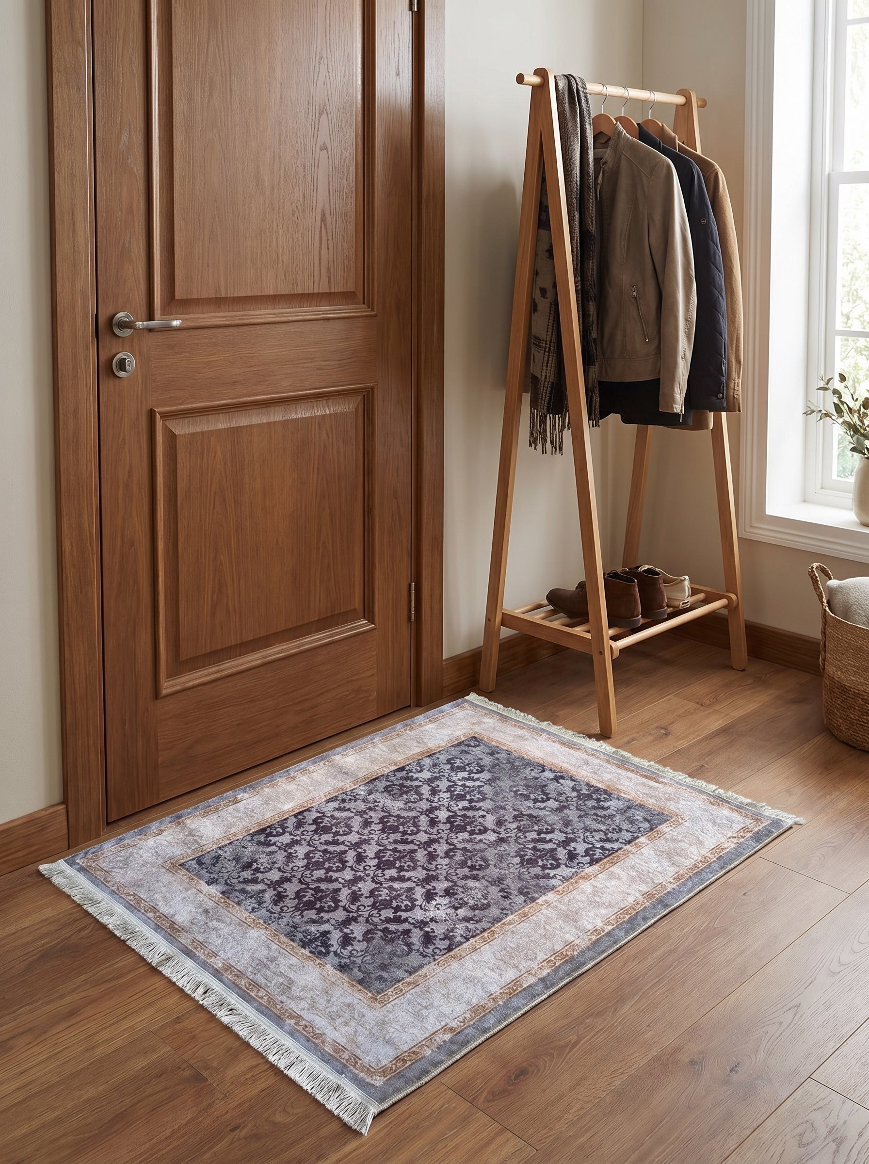 Tapis rectangulaire à motifs floraux délavés violets et gris avec bordure claire et franges, sur parquet dans une entrée