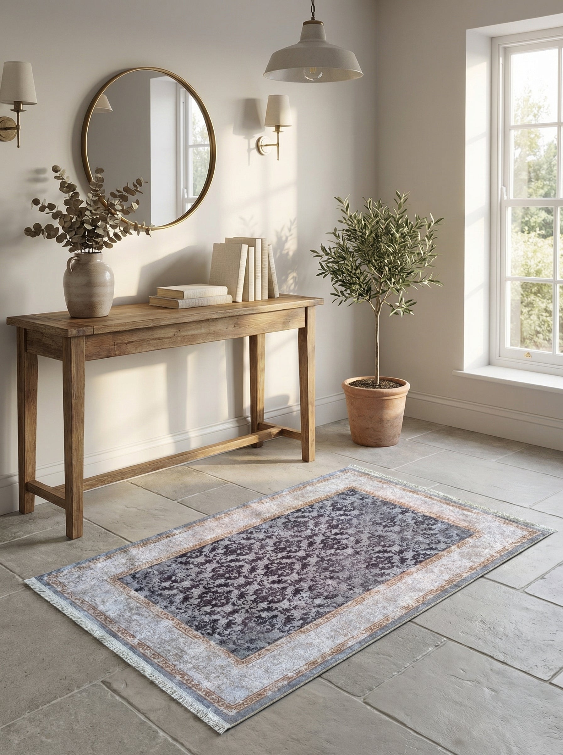 Tapis rectangulaire aux motifs floraux foncés sur fond gris-bleu vieilli, bordures claires et franges, dans une entrée lumineuse