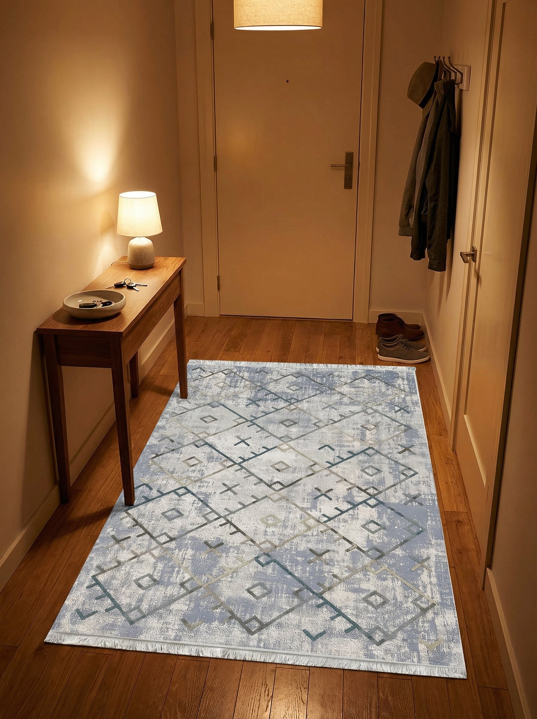 Tapis rectangulaire clair à motifs géométriques bleus et gris sur fond abstrait blanc et bleu, posé dans une entrée