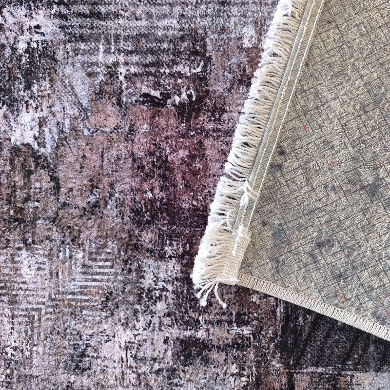 Tapis aux motifs abstraits et aspect vieilli, teinté de marron, pourpre et gris, avec des franges et l'envers visible