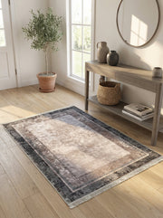 Tapis rectangulaire dégradé du beige clair au gris anthracite, avec motifs abstraits et géométriques, frangé, sur un parquet en bois clair d'une entrée