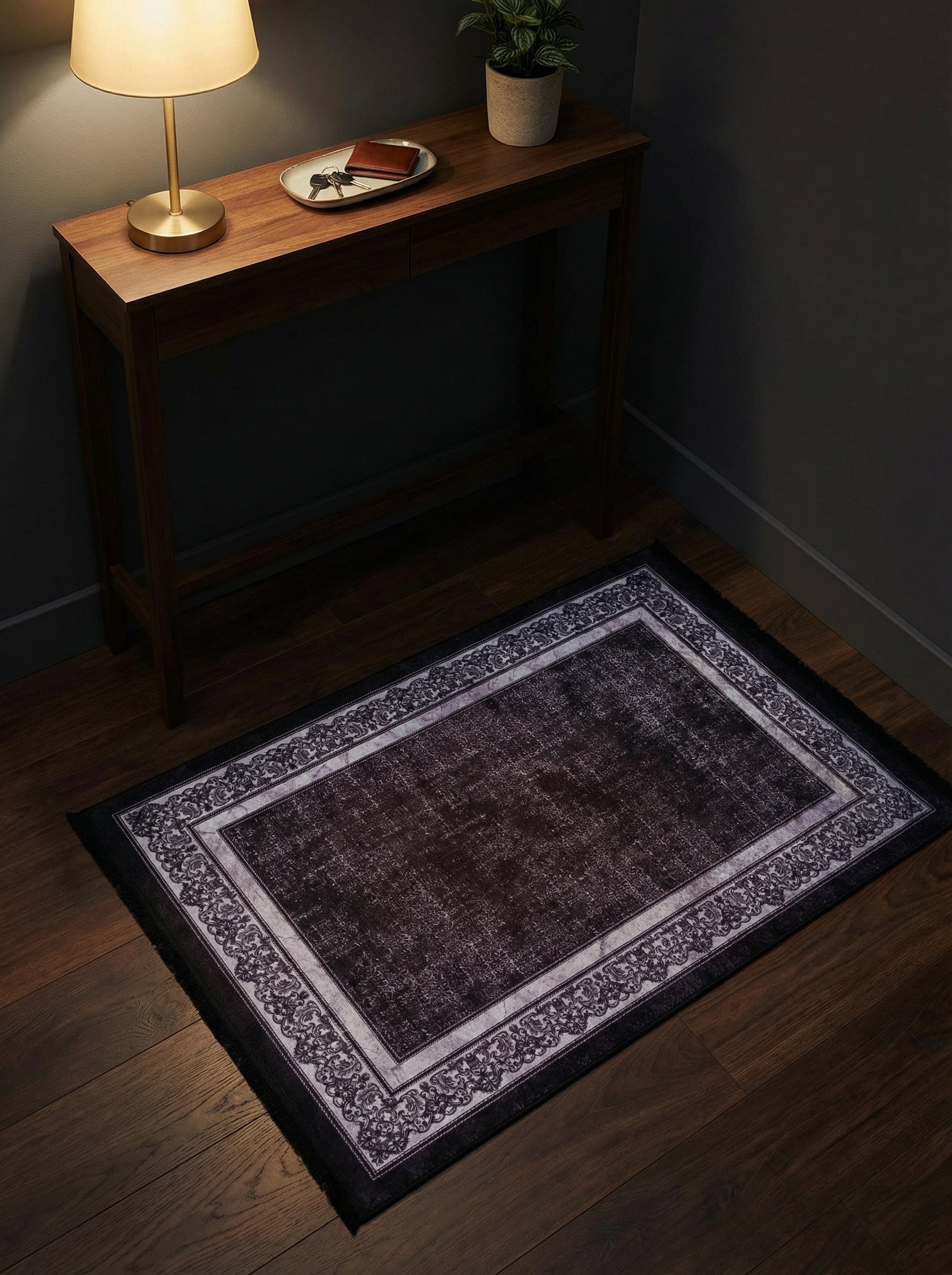 Tapis rectangulaire marron foncé vieilli avec large bordure gris clair à motifs floraux sombres, sur parquet d'entrée