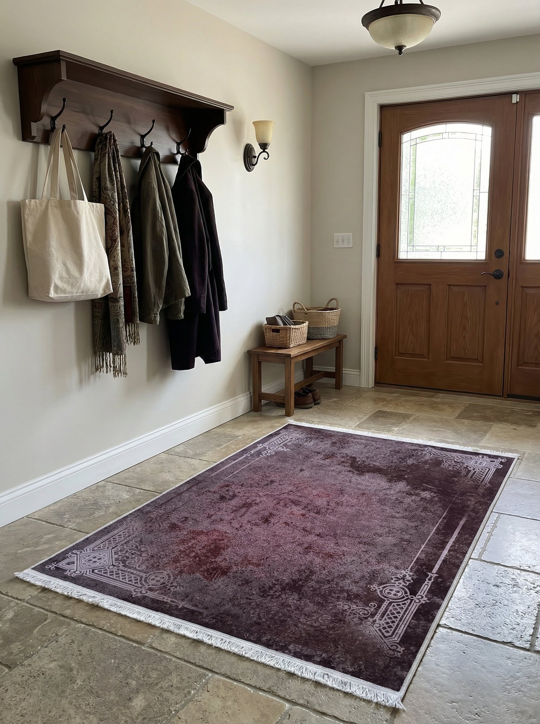 Tapis rectangulaire bordeaux à motifs ornementaux gris clair et franges blanches, posé sur un sol carrelé dans une entrée