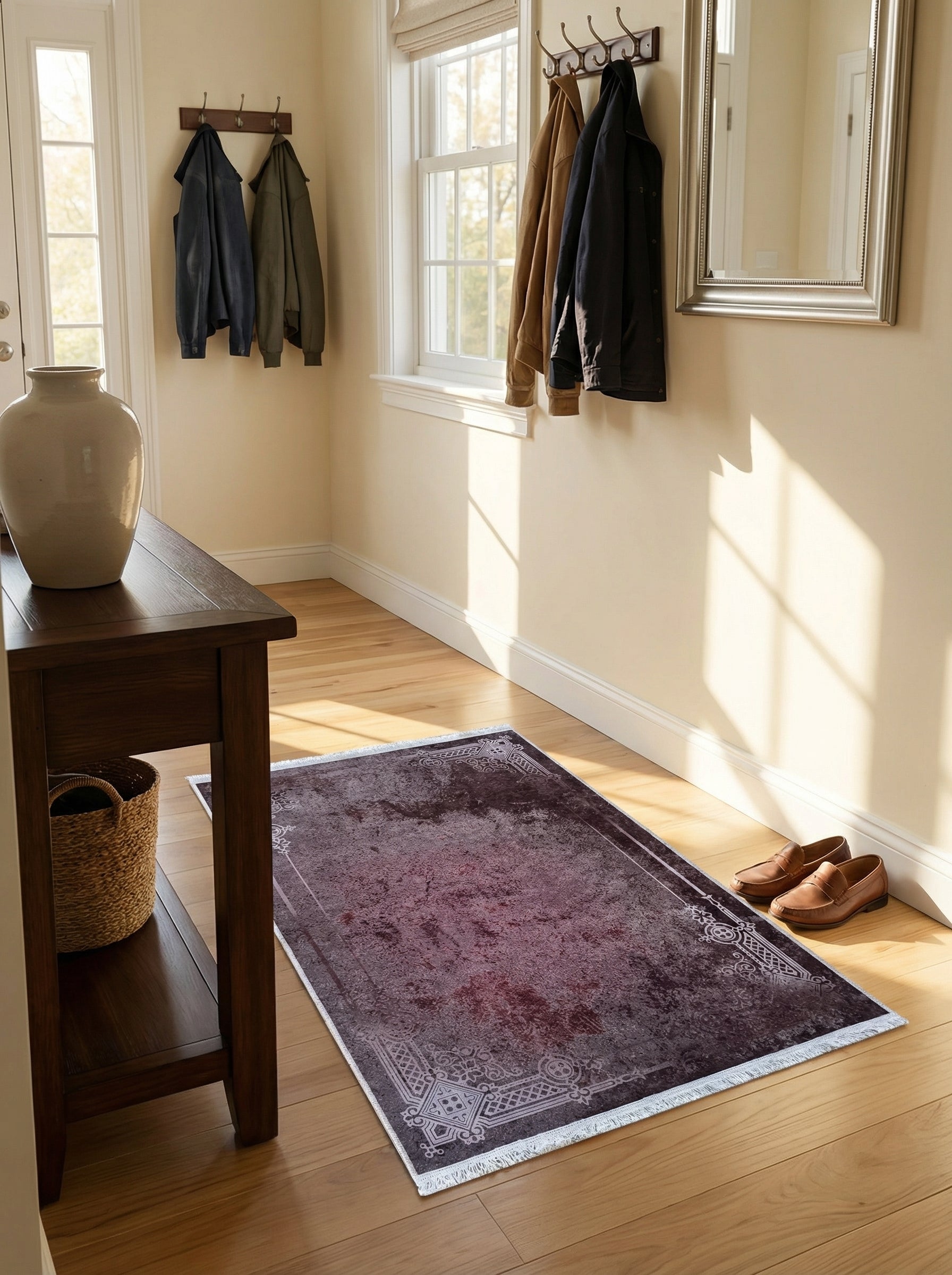 Tapis rectangulaire bordeaux vieilli à motifs ornementaux clairs sur les bordures, sur parquet dans une entrée lumineuse