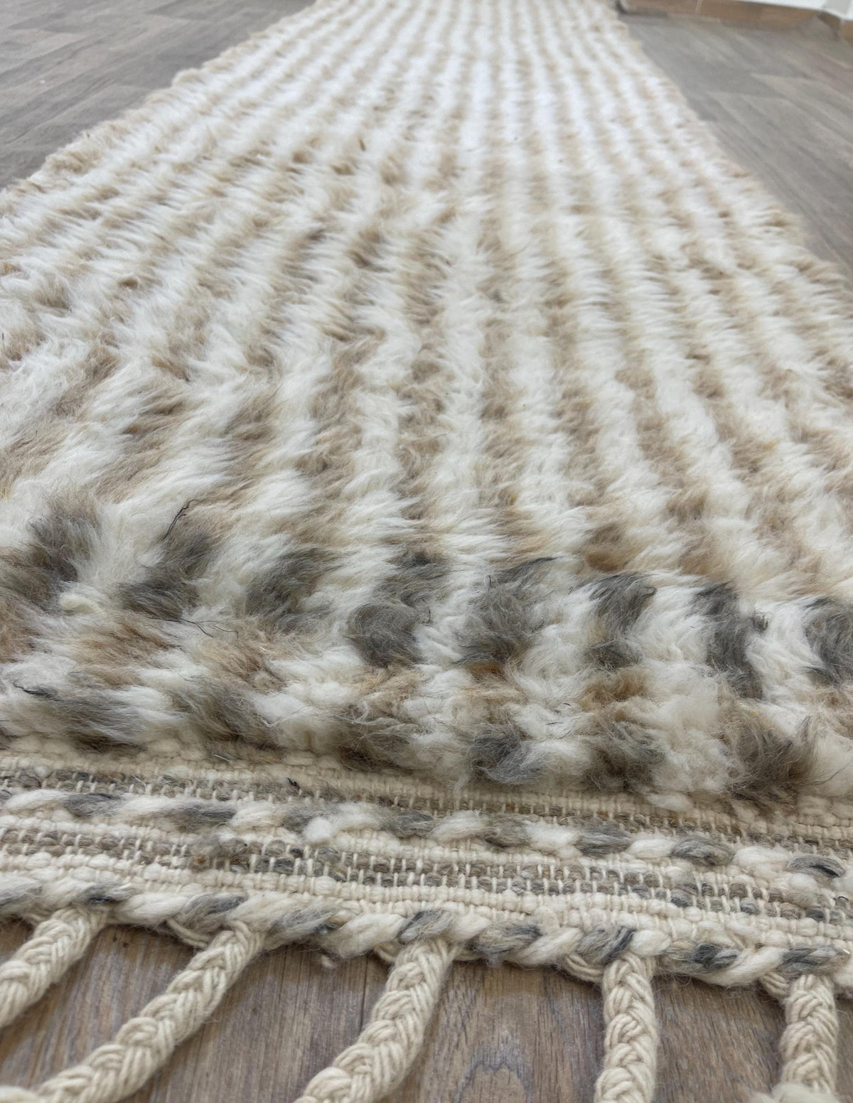 Tapis d'escalier berbère à rayures beige et blanc Tamri posé au sol vu de côté, noué main au Maroc