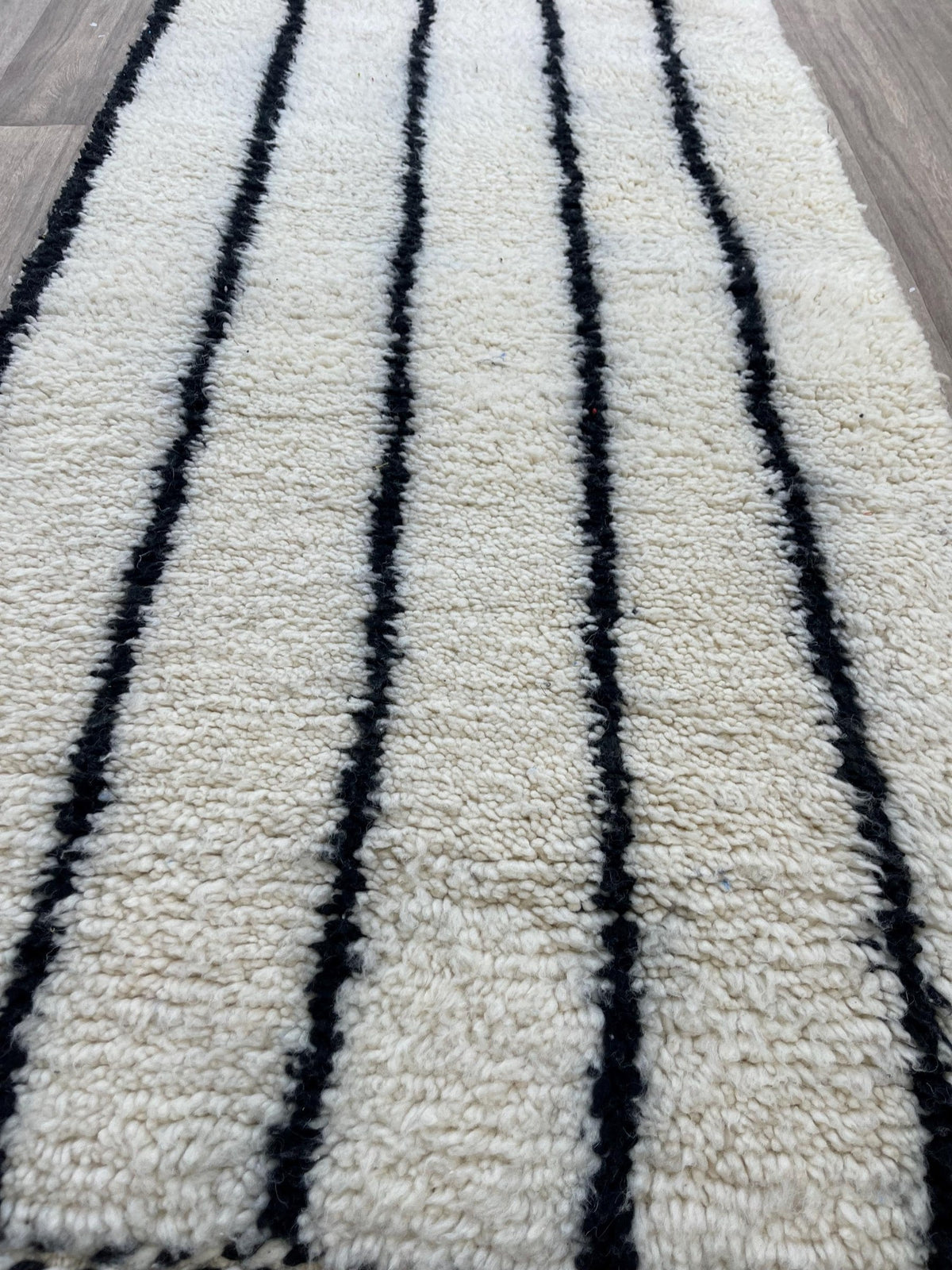 Gros plan sur la laine du tapis d'escalier berbère Iberdan, nœuds serrés et tracé du motif de près