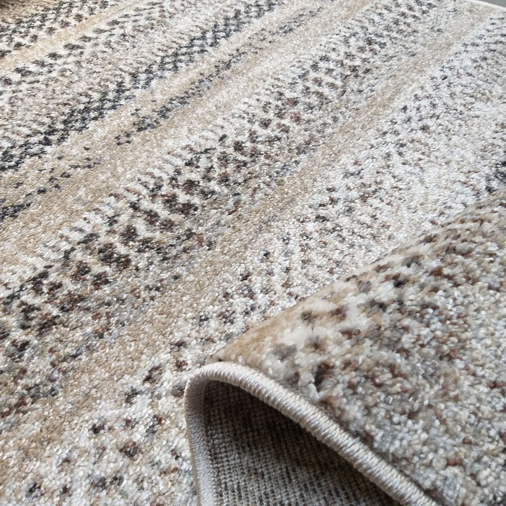 Tapis à poil court avec motifs de bandes abstraites tachetées beiges, crème et marron foncé, et un bord roulé