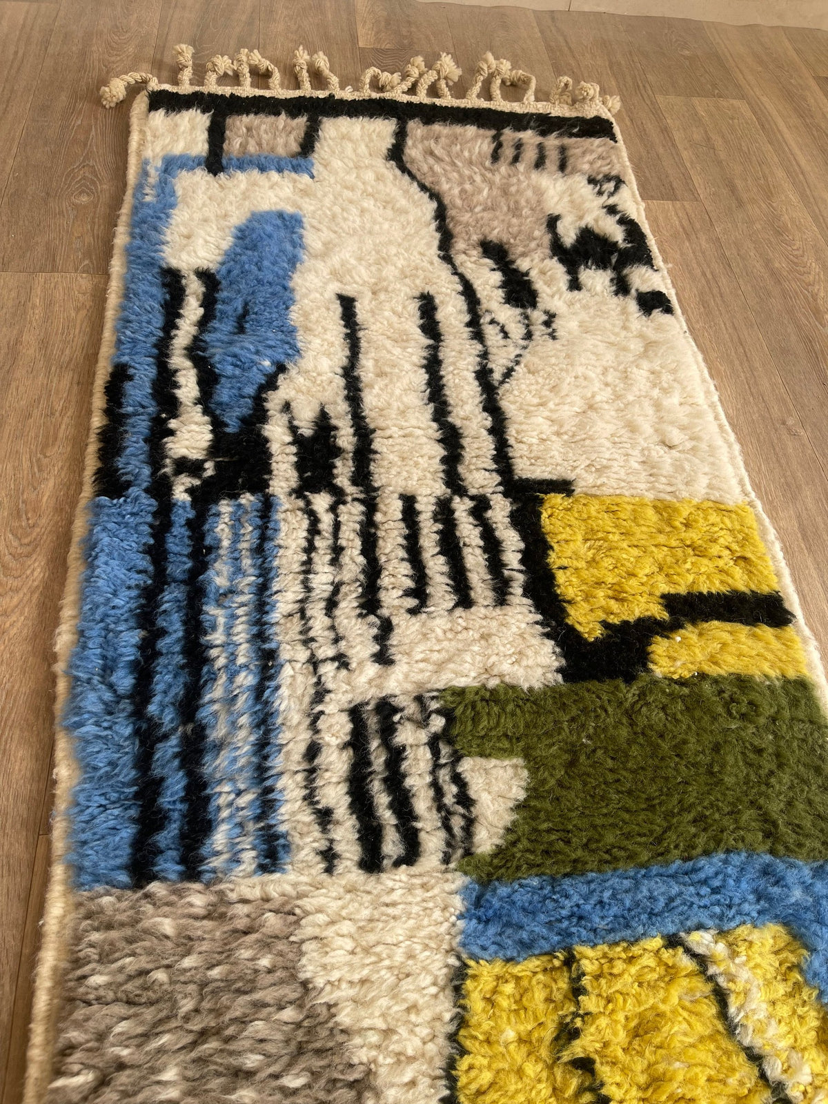 Gros plan sur un détail du tapis d'escalier berbère Iznagal, poil long et motif jaune et bleu vus de près, vue 4