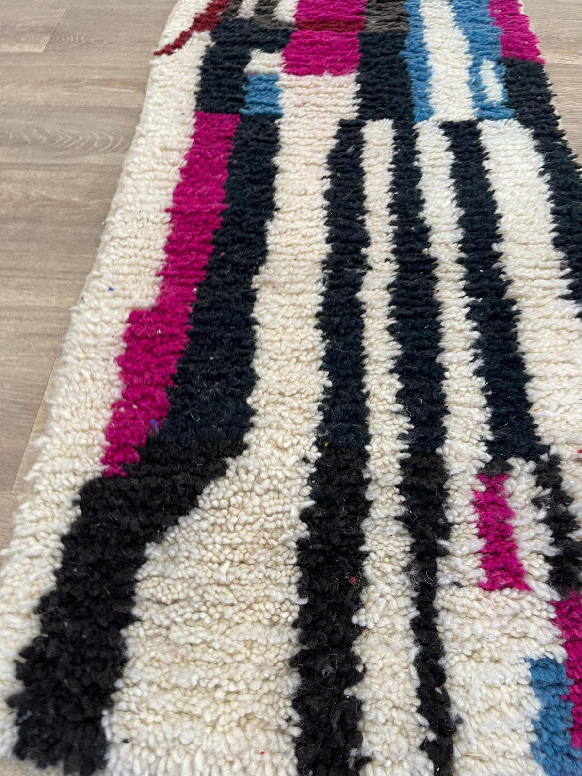 Gros plan sur la laine du tapis d'escalier berbère Zerouan, laine de mouton au poil long, noire et fuchsia