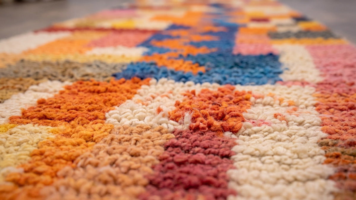Gros plan sur la laine du tapis d'escalier berbère Anzarane, poil orange et bleu noué à la main