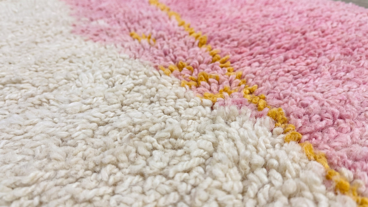 Gros plan sur la laine du tapis d'escalier berbère Tanmila, poil rose et blanc noué à la main