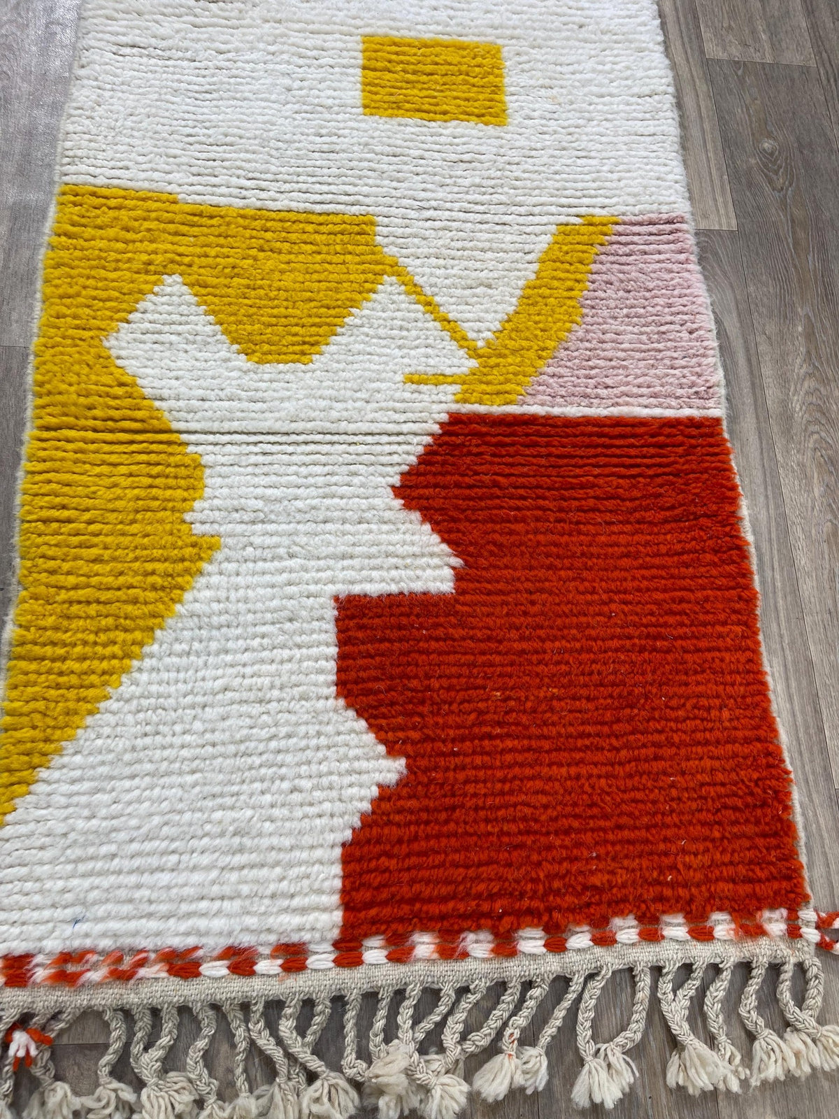 Gros plan sur un détail du tapis d'escalier berbère Farsia, poil moyen et motif rouge et jaune vus de près