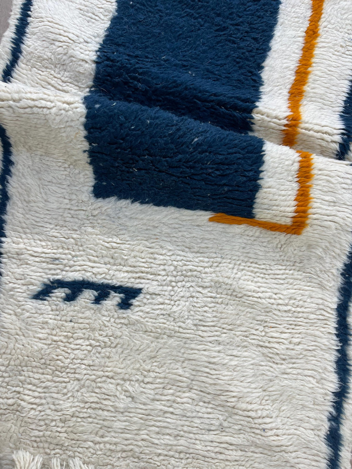 Gros plan sur un détail du tapis d'escalier berbère Bouregreg, poil long et motif blanc et bleu vus de près