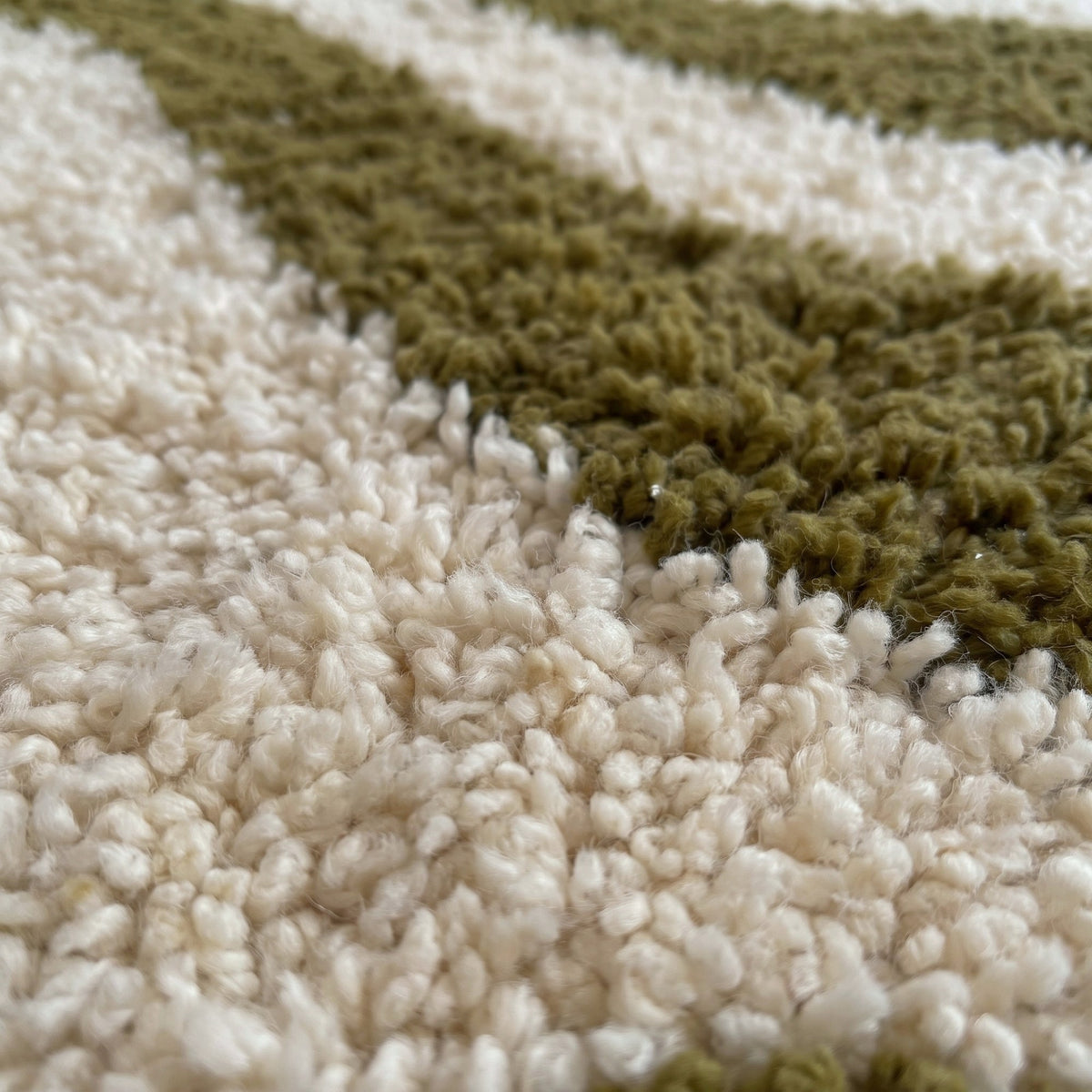 Close-up of a motif on the Assaka Berber stair runner, ecru runner, wide winding olive green wave