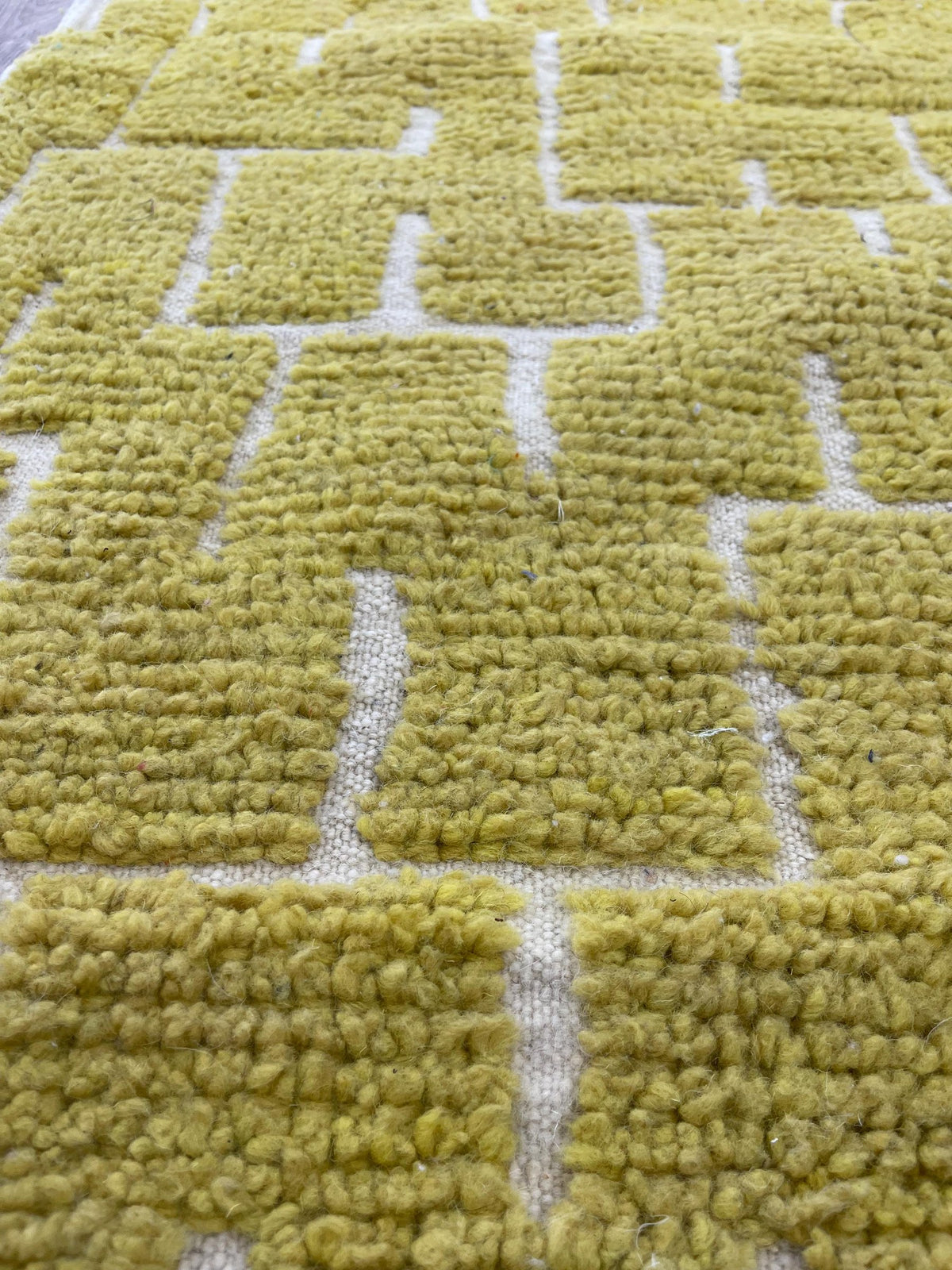 Gros plan sur la laine du tapis d'escalier berbère Timzin, nœuds serrés et tracé du motif de près