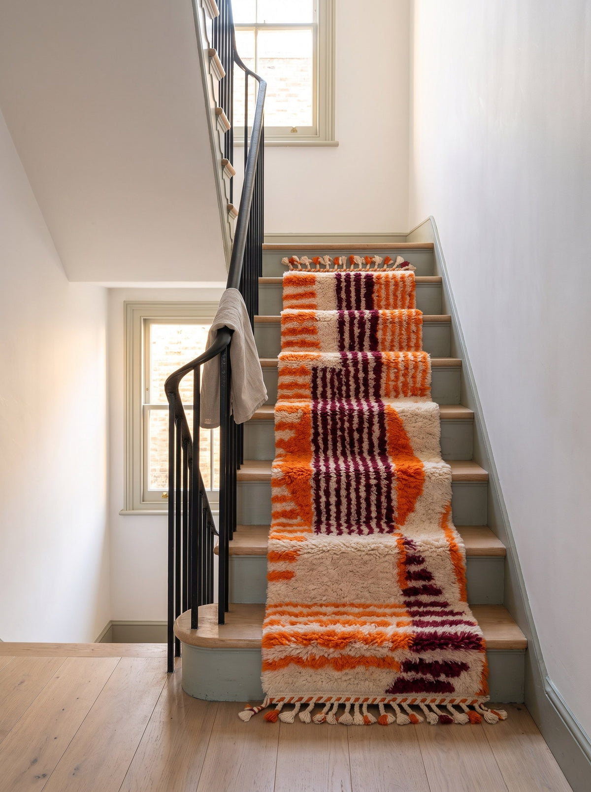 Tapis d'escalier berbère graphique orange et bordeaux Melgad sur un autre escalier, noué main au Maroc