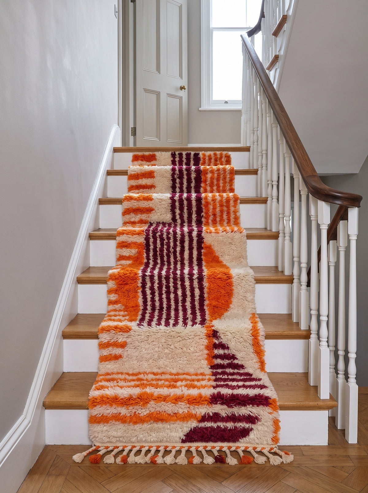 Tapis d'escalier berbère graphique orange et bordeaux Melgad sur un escalier, noué main au Maroc