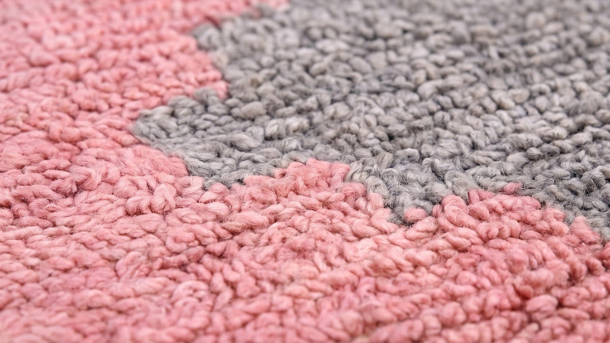 Gros plan sur la laine du tapis d'escalier berbère Timzila, poil rose et gris noué à la main