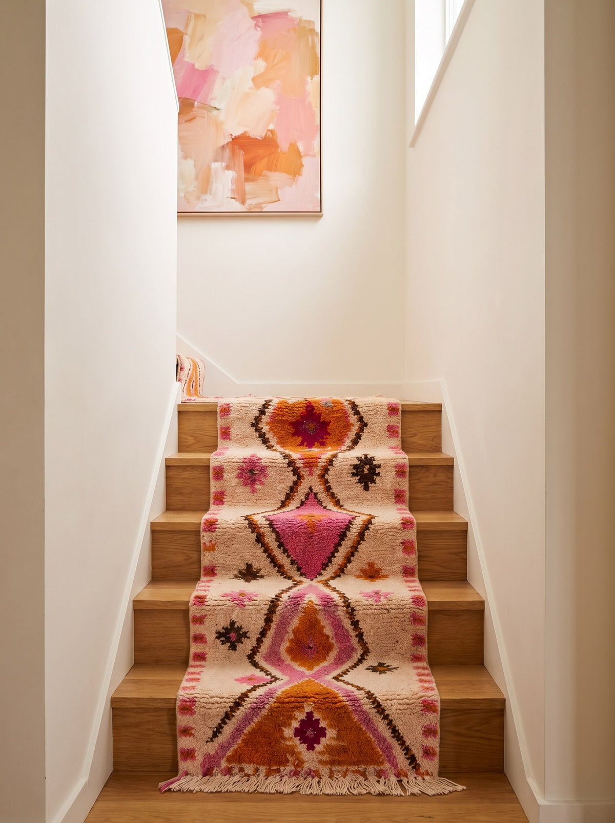 Tifawin Berber stair runner, Azilal style, in white, orange and pink on a staircase, hand-knotted in Morocco