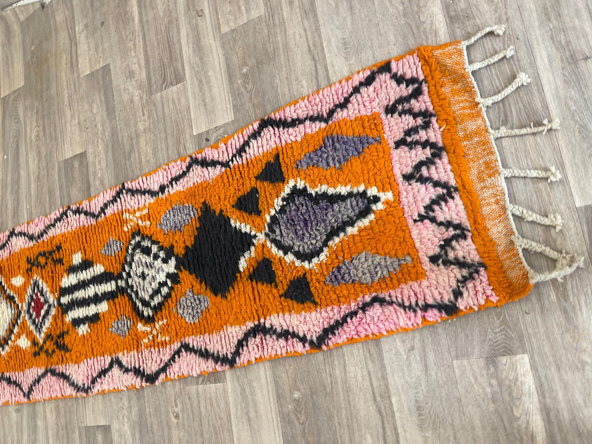 Close-up of a detail on the Khamlia Berber stair runner, medium pile and pattern in orange and pink up close
