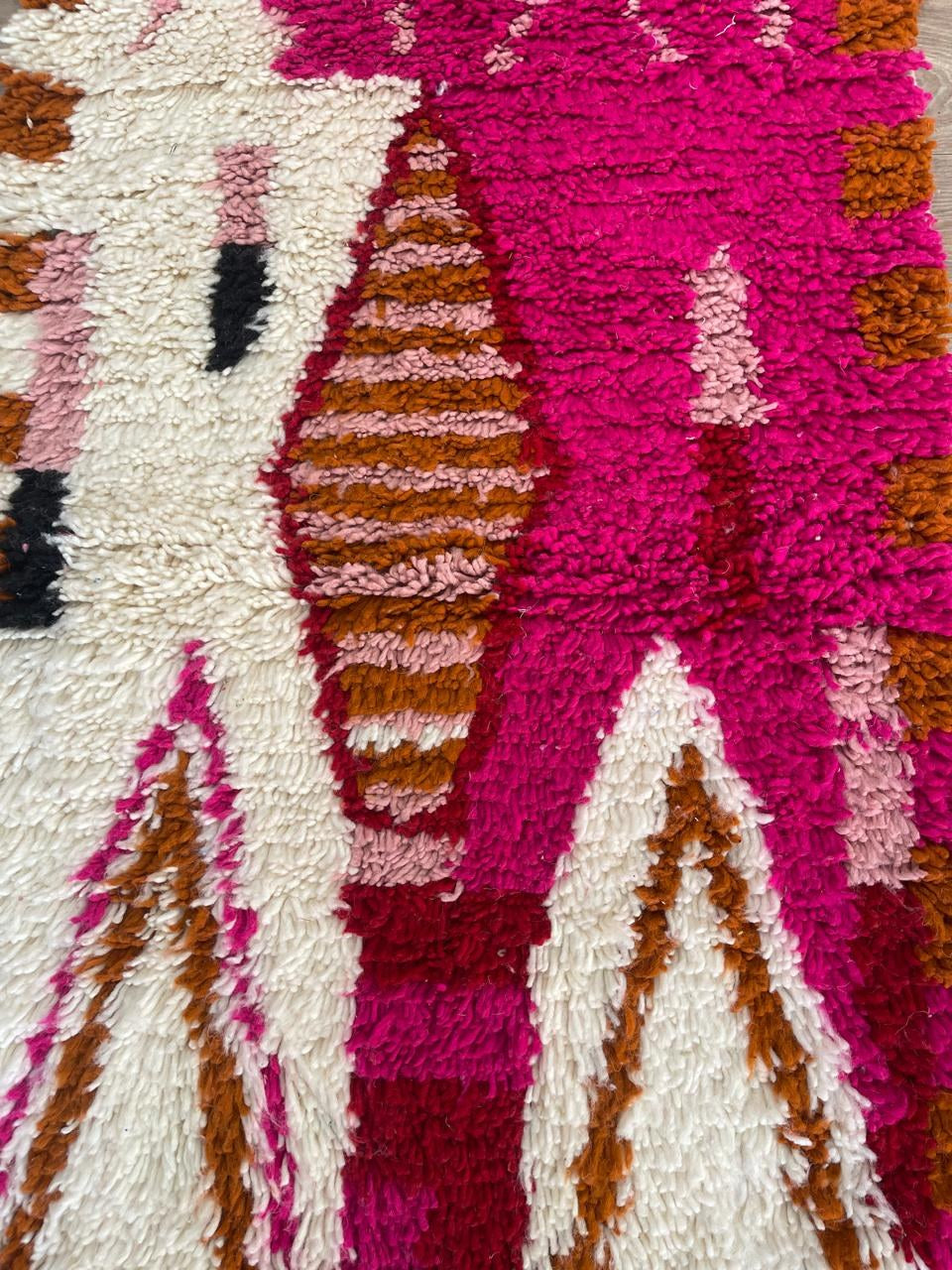 Gros plan sur un détail du tapis d'escalier berbère Anoura, poil long et motif rose fuchsia vus de près