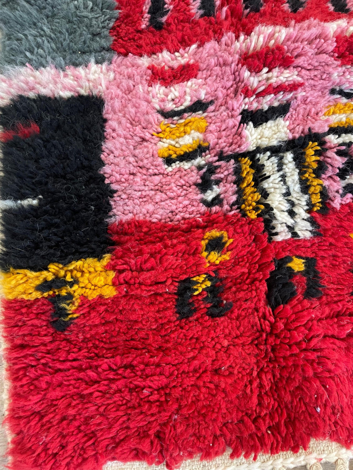 Gros plan sur la laine du tapis d'escalier berbère Rassira, laine de mouton au poil long, rouge et rose
