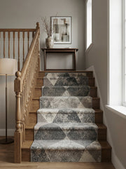 Tapis d'escalier texturé aux motifs géométriques triangulaires gris clair, gris foncé et beige, dans un hall d'entrée