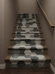 Tapis d'escalier texturé aux motifs hexagonaux alternant gris clair et anthracite, recouvrant des marches en bois dans un couloir