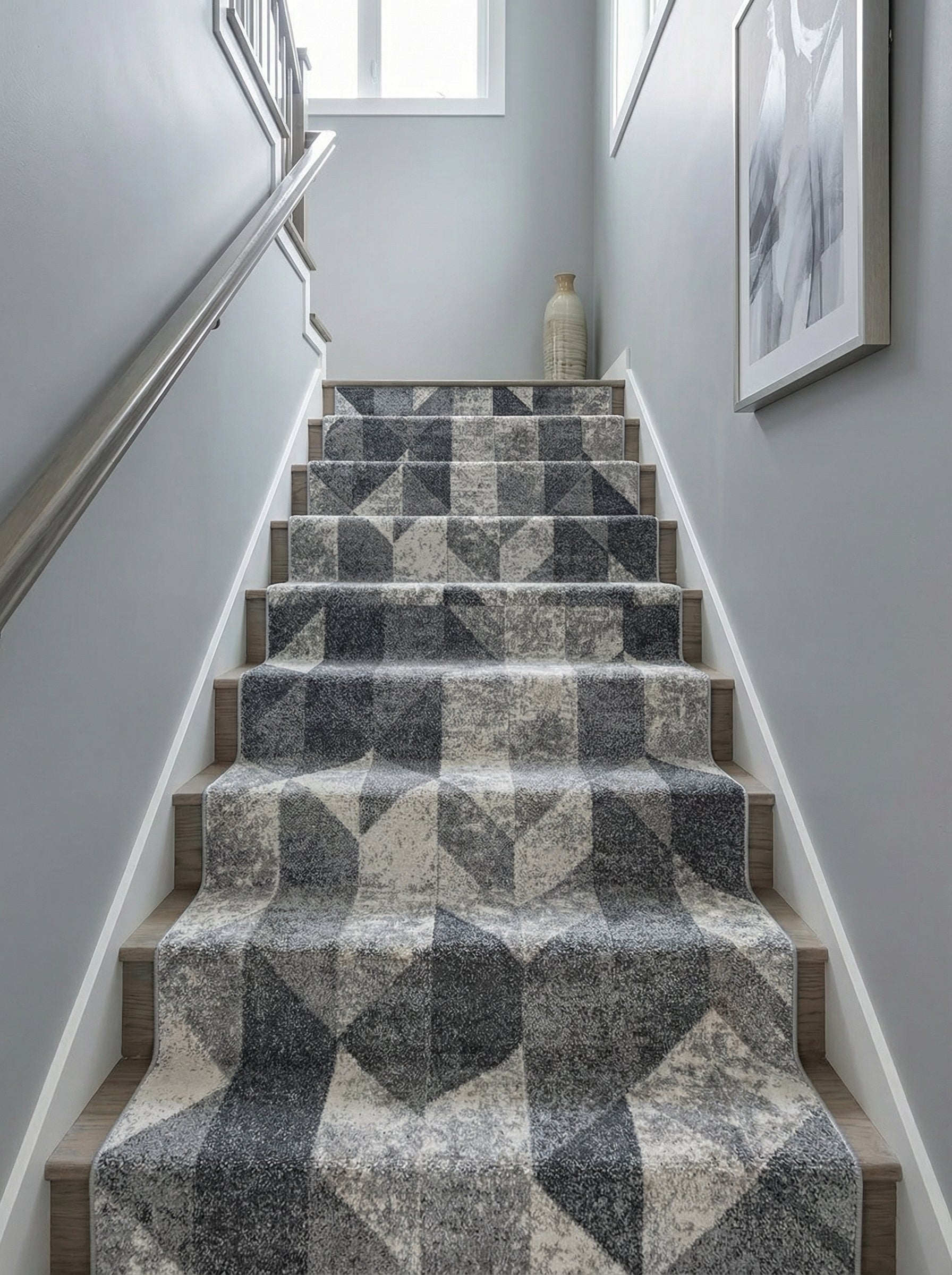Tapis d'escalier gris clair et foncé avec motif géométrique cubiste sur des marches en bois dans une cage d'escalier contemporaine
