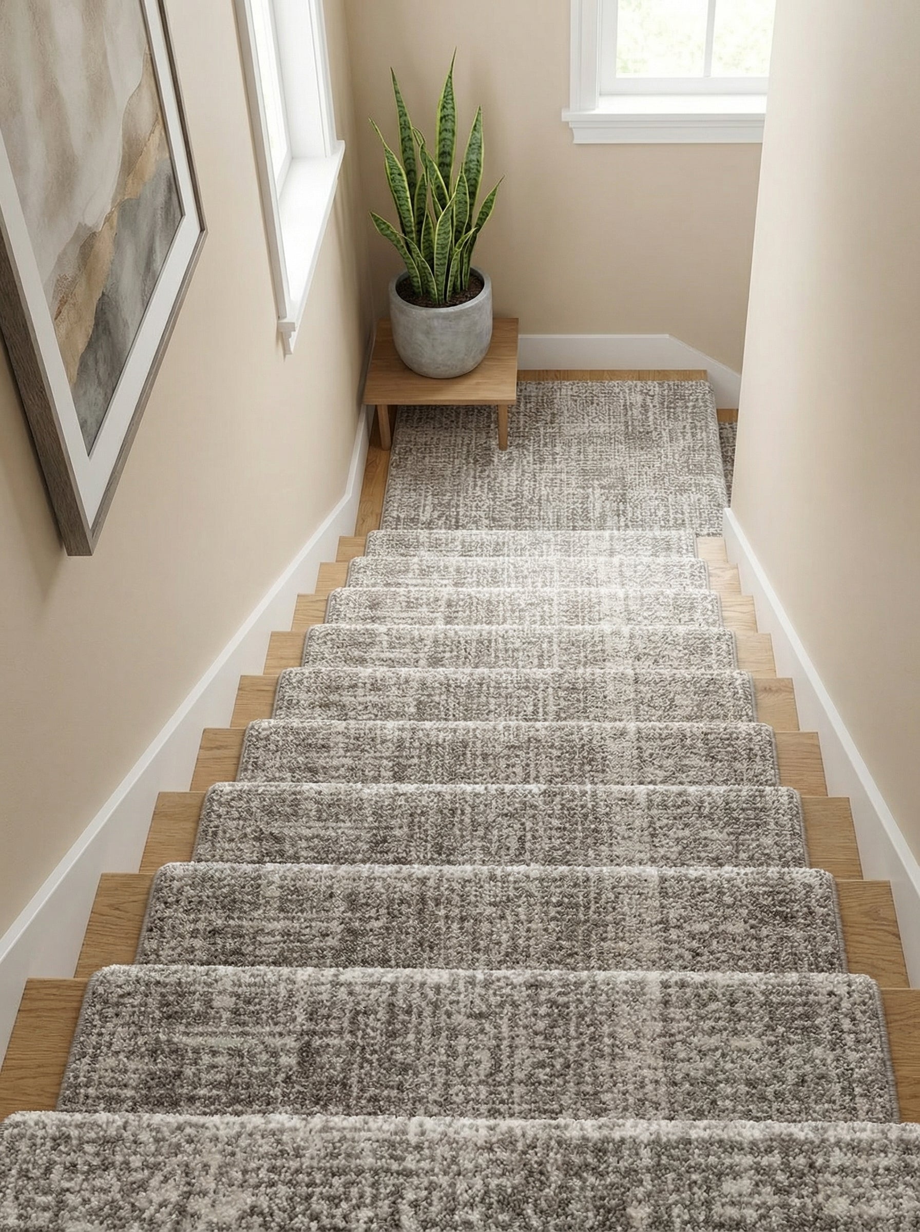 Tapis d'escalier gris chiné texturé recouvrant des marches en bois clair, descendant dans un hall d'entrée