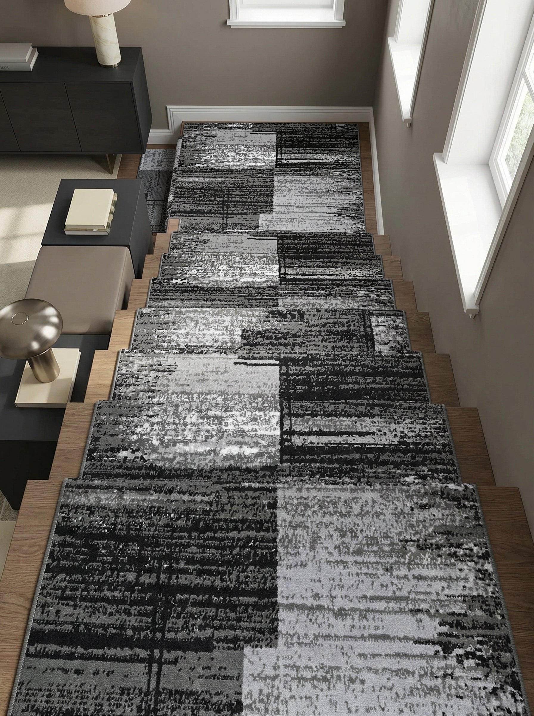 Tapis d'escalier contemporain au design abstrait de blocs gris, noirs et blancs, sur des marches en bois d'un couloir