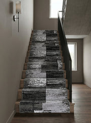 Tapis d'escalier en tissu aux motifs abstraits noirs, gris et blancs en blocs alternés, sur des marches en bois d'une entrée moderne