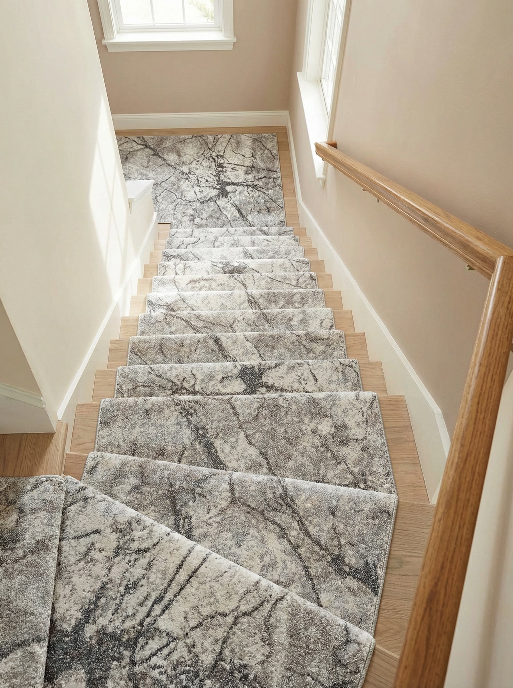 Tapis d'escalier à motifs abstraits gris clair et foncé, veinés comme du marbre ou des branches, posé sur les marches d'une cage d'escalier lumineuse