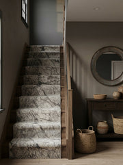 Tapis d'escalier clair aux motifs de veines grises foncées, posé sur des marches en bois dans une entrée moderne et sombre