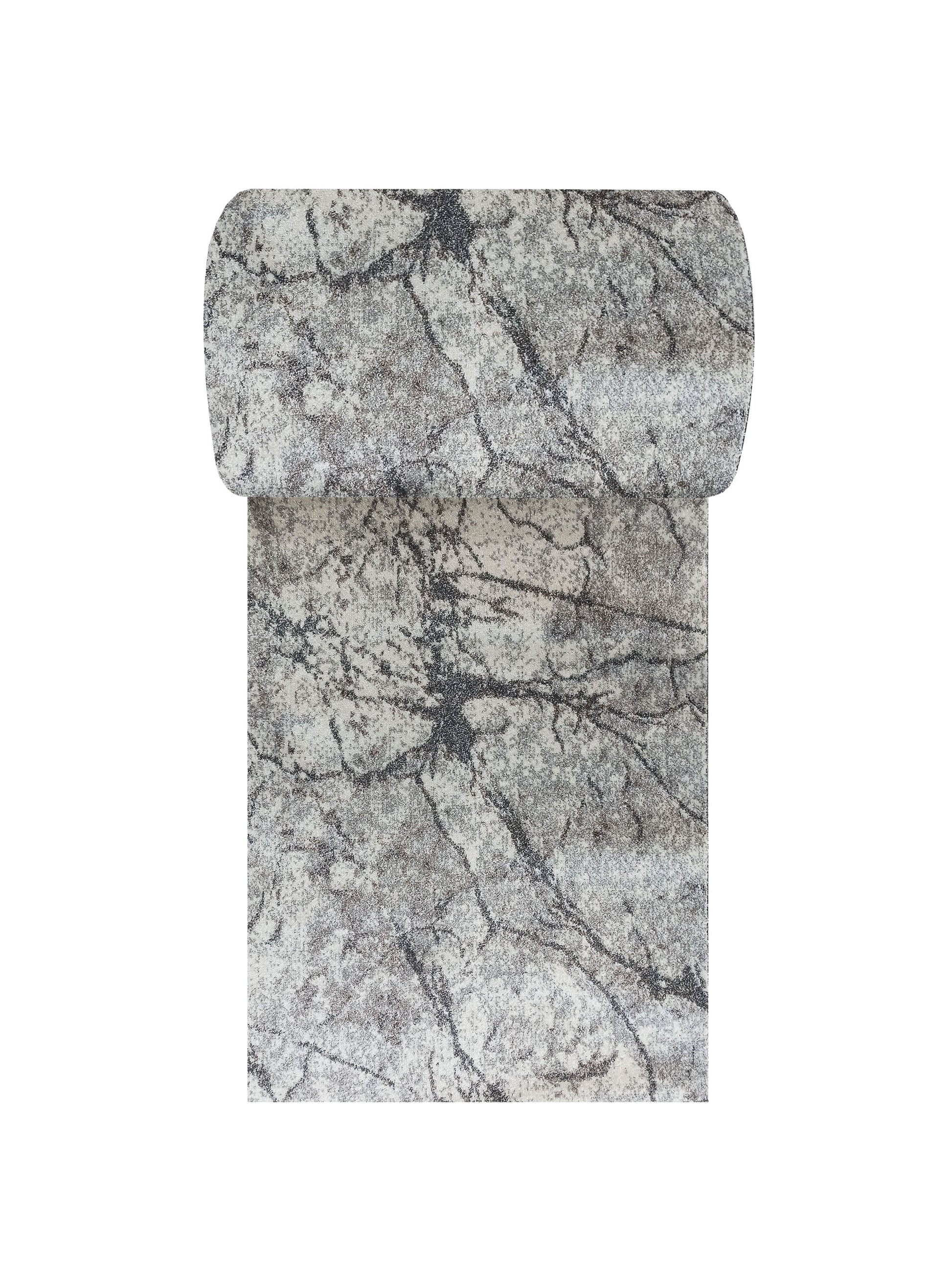 Tapis textile aux tons gris et blancs, avec des motifs de veinures irrégulières sombres, partiellement roulé