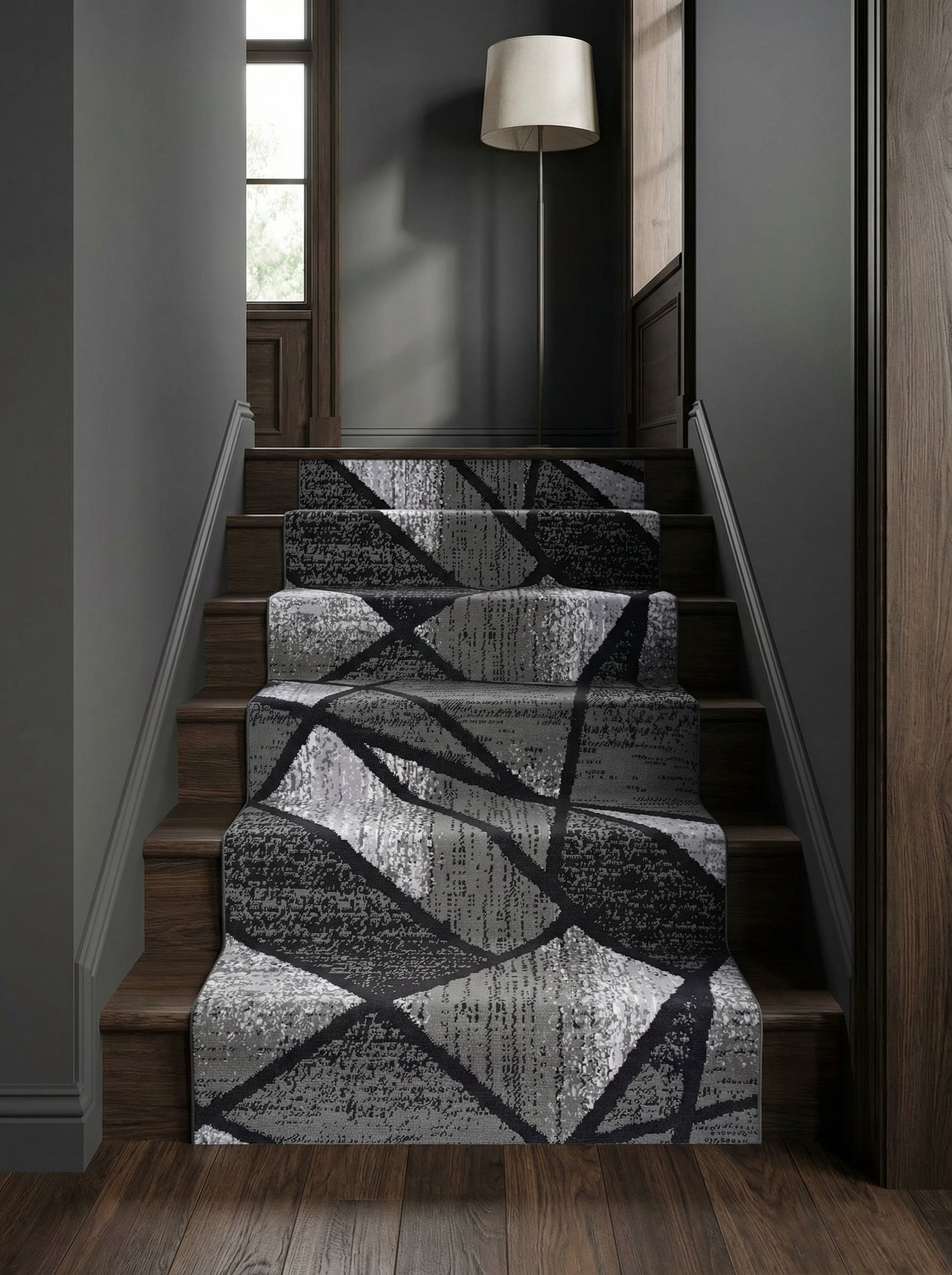 Tapis d'escalier gris, noir et blanc aux motifs géométriques abstraits texturés, sur des marches en bois foncé dans un hall
