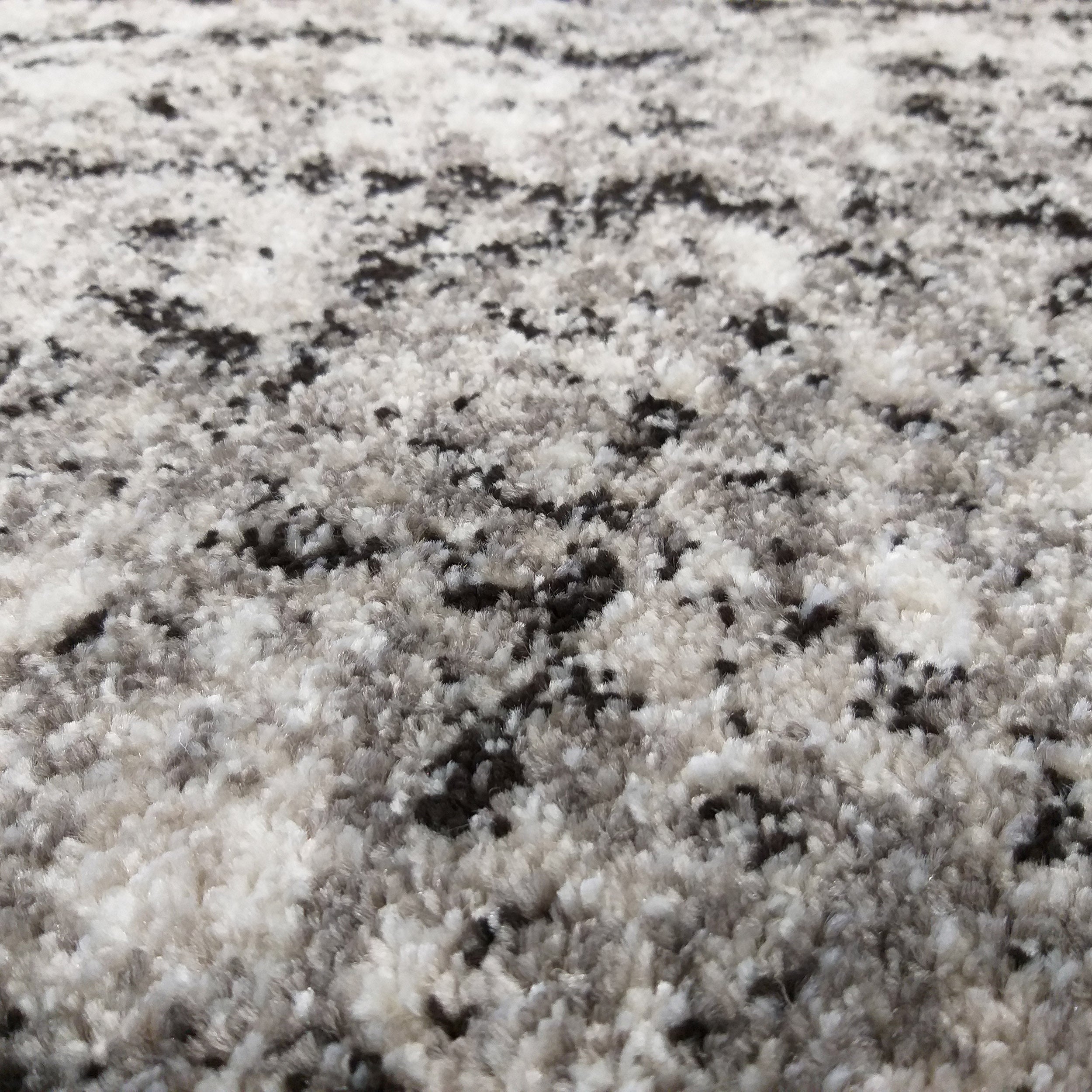 Tapis à poils longs avec un motif abstrait mêlant des fibres blanches, grises et noires