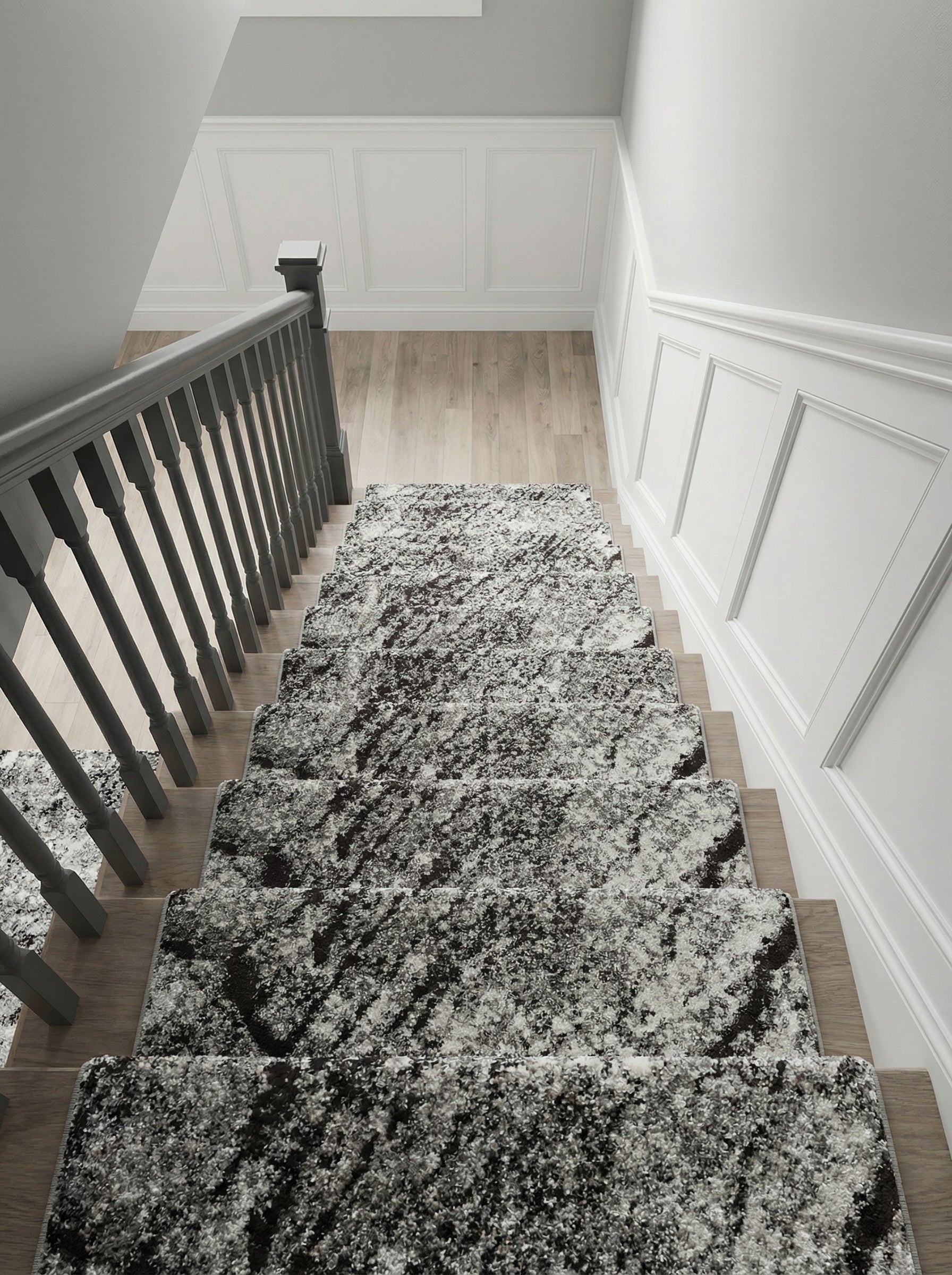 Tapis d'escalier abstrait aux nuances de noir, blanc et gris, recouvrant des marches en bois clair, dans un hall d'entrée lumineux