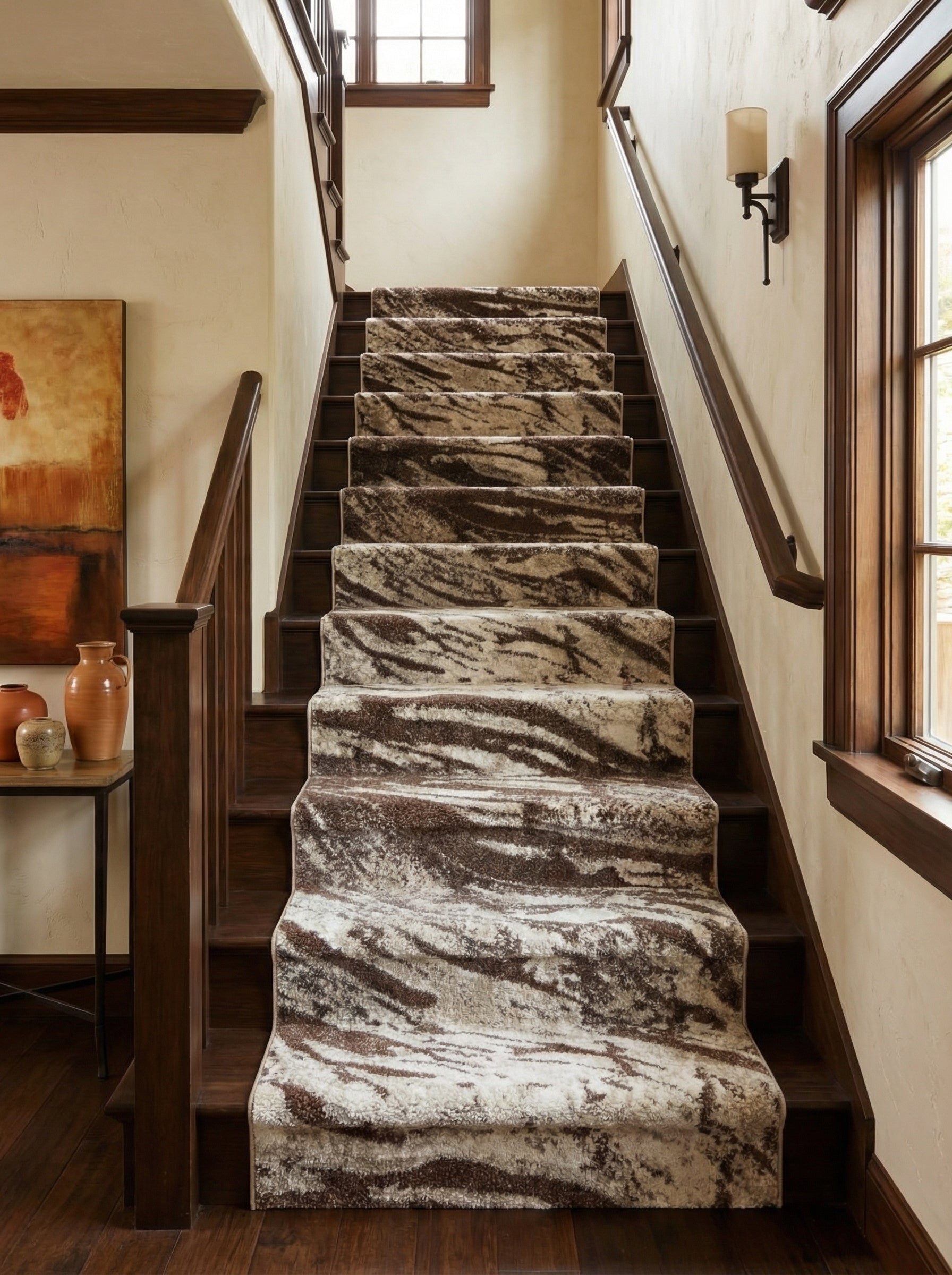 Tapis d'escalier moelleux, crème et marron aux motifs abstraits comme des coups de pinceau, recouvrant des marches en bois dans un hall