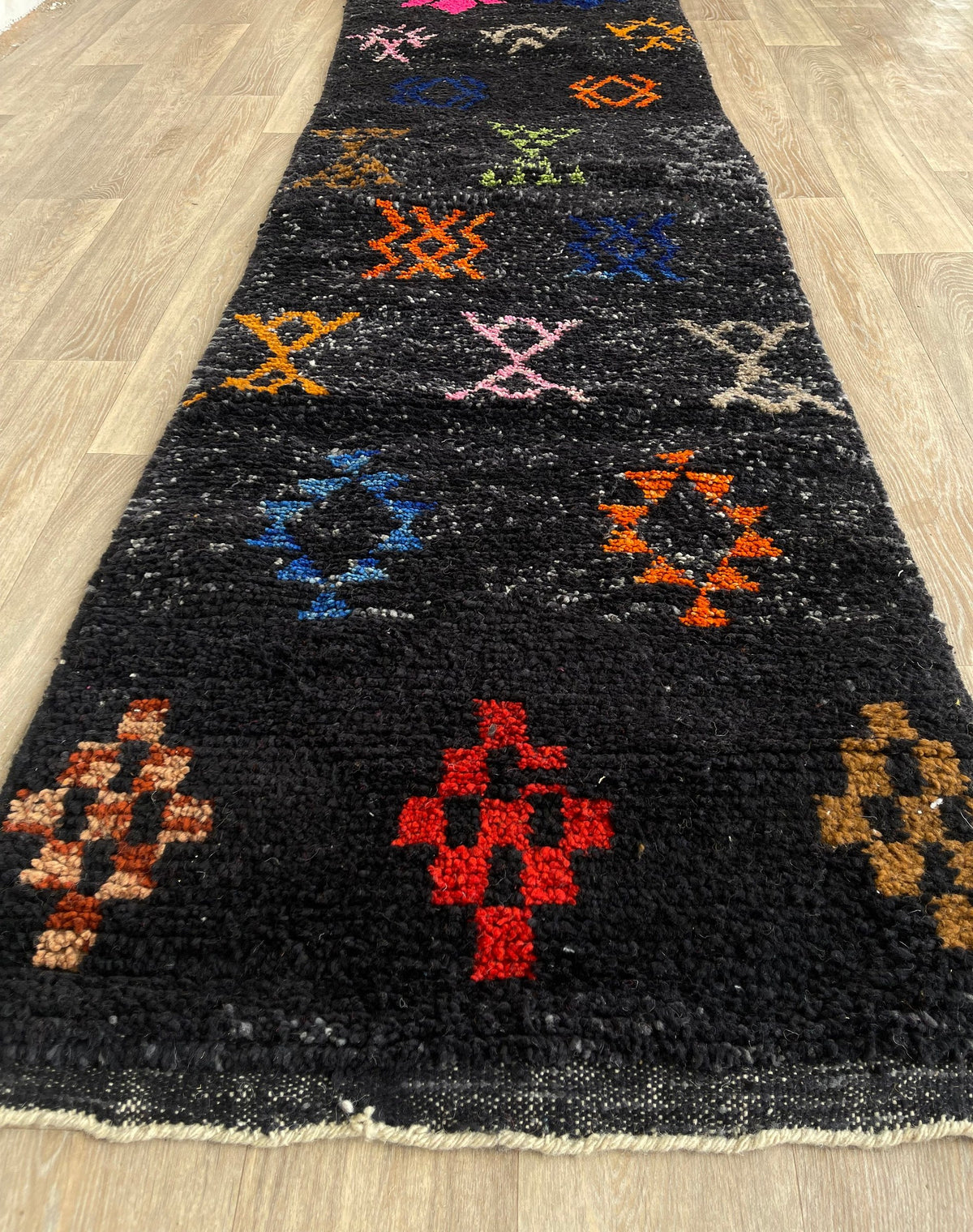 Tapis de couloir berbère à motifs noir multicolore Zemilt posé au sol vu de côté, noué main au Maroc