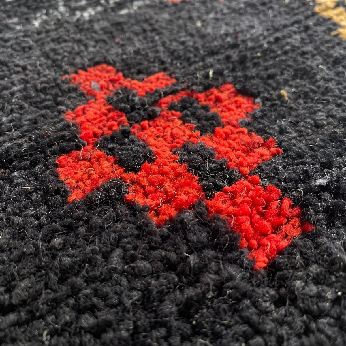Gros plan sur un motif du tapis de couloir berbère Zemilt, couloir fond noir chiné, huit rangées de symboles